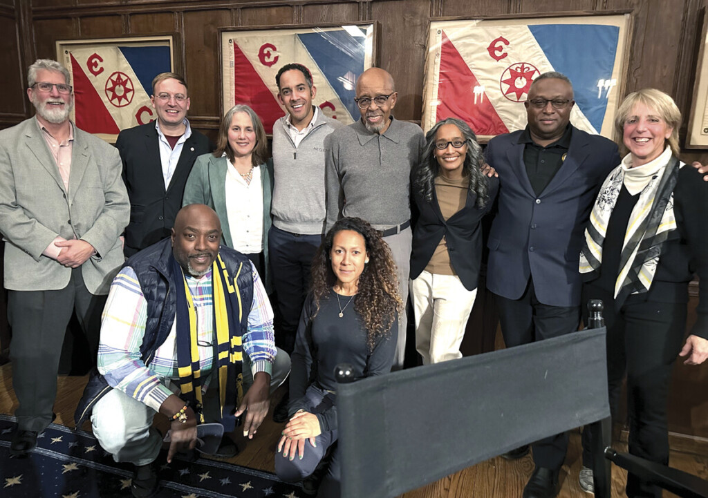 Members of the Explorer’s Club and attendees pose in front of retired flags carried on major scientific expeditions. Today, there are over 200 numbered flags, each with its own history on display.