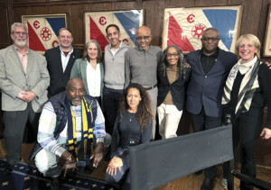 Members of the Explorer’s Club and attendees pose in front of retired flags carried on major scientific expeditions. Today, there are over 200 numbered flags, each with its own history on display.