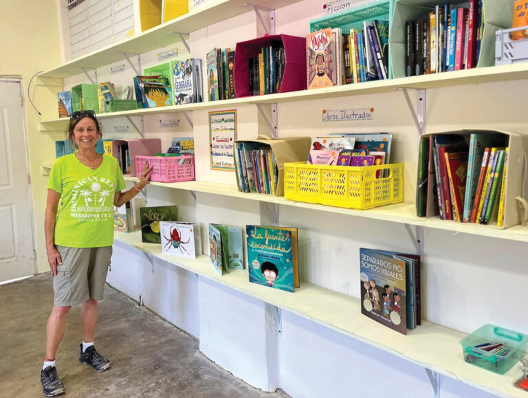 Donna stands happily by the shelves of the new library at the Fundacion Fuente de Esperanza School at San Marcos.