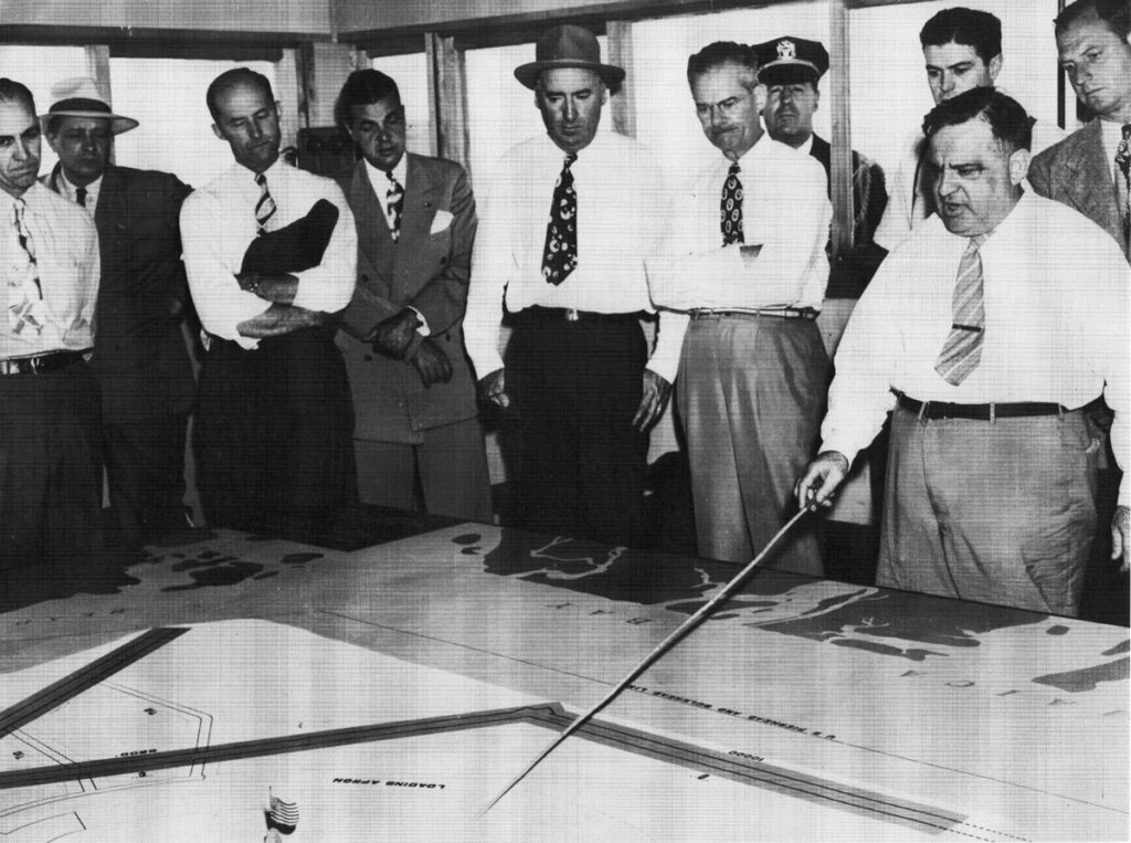 Fiorello La Guardia New York Airport Mayor La Guardia in boardroom explaining model of New York International Airport (Idlewild) to businessmen. La Guardia pushed through construction of Idlewild in 1940s. (Cradle of Aviation Museum)
