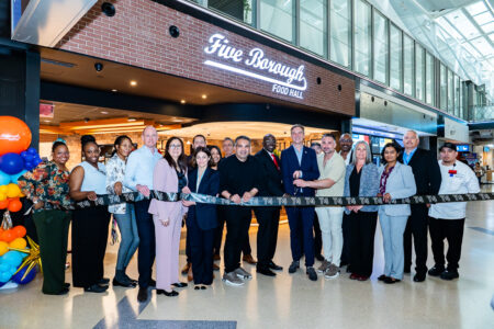 SSP America, a division of SSP Group, a leading operator of food and beverage brands in travel locations worldwide, together with JFKIAT, the operator of Terminal 4 at John F. Kennedy International Airport, today announced the reopening of the refreshed Five Borough Food Hall, SSP America’s proprietary New York-inspired food hall concept at JFK Terminal 4. The reopening was celebrated with a ribbon cutting at Terminal 4 on May 21, bringing together representatives from JFKIAT, SSP America, For Five Coffee Roasters, joint venture partners, airport leaders, and the teams behind the refreshed dining experience. Since its debut, Five Borough Food Hall has been recognized as one of SSP America’s signature proprietary concepts, earning AXN’s Best New Concept award in 2018 and FAB Awards’ Airport Street Food Offer of the Year in 2018. Originally created by SSP America in partnership with JFKIAT, Five Borough Food Hall has been reimagined for today’s traveler while preserving the energy, variety, and unmistakable New York spirit that made the concept a standout at Terminal 4. The refreshed food hall brings together a broad all-day lineup including For Five Coffee Roasters, Dromos Fresh Greek Food, Mango Taco Truck, Five Borough Food Hall Deli, and 5BFH Pizza, offering travelers everything from locally roasted coffee and pastries to Greek-inspired bowls, tacos, burritos, New York deli sandwiches, pizza, salads, and grab-and-go items. As the international terminal of JFK, Terminal 4 is where America greets the world — and where Big City dining starts before the journey begins. Today, Terminal 4 spans more than two million square feet, serves more than 27 million passengers annually, houses 21 airlines, and supports a community of 12,000 employees. In a terminal defined by movement, diversity, and global connection, Five Borough Food Hall offers a dining experience designed to meet the moment: fast when travelers need speed, varied when they want choice, and unmistakably rooted in New York. The refreshed design moves the original concept forward from its food-truck hall roots into a modern New York neighborhood market. Warm wood details, brick textures, mural-wrapped columns, subway-inspired tile, bold menu graphics, branded refrigerated cases, and open service counters create a layered sense of place that nods to the streets, storefronts, delis, slice shops, coffee counters, and global flavors found across the five boroughs. “Five Borough Food Hall has always captured what makes New York such an extraordinary food city: its pace, diversity, and creativity,” said George Mboya, CEO of SSP America. “This refresh marks an exciting new chapter for a concept created specifically for JFK Terminal 4 and a key part of our partnership with JFKIAT. Together, we’re continuing to deliver authentic dining experiences that reflect the city outside the terminal and bring the best part of the journey to life for our travelers.” “Marking the reopening of Five Borough Food Hall at JFK T4 is a significant milestone as we continue to elevate the terminal experience for our passengers,” said Roel Huinink, Chief Executive Officer of JFKIAT. “Thanks to our long-lasting partnership with SSP America, who have been instrumental throughout our 25-year journey, passengers at T4 will have access to a curated selection of exceptional culinary options, offering a New York sense of place that aligns with the Port Authority’s vision for JFK. The addition of For Five Coffee Roasters exemplifies that vision, and we’re very pleased that this local Queens-based business will have the opportunity to enter the airport concessions space for the first time with the benefit of SSP’s global expertise and mentorship.” A key part of the refreshed offer is the addition of For Five Coffee Roasters, the Queens-born specialty coffee company known for small-batch roasting, premium beans, and cafés designed around craft, hospitality, and New York energy. Its Five Borough Food Hall menu includes hot and iced espresso drinks, cold brew, matcha, chai, pastries, and signature beverages including The Five and The Louie. "Opening our first airport location at JFK is a milestone that feels especially meaningful because it brings us back to where our story began — Queens,” said Stefanos Vouvoudakis, Co-Founder and CEO of For Five Coffee Roasters. “For Five was built to redefine what coffee hospitality could look like — combining elevated design, exceptional product, and a level of service that delivers a luxury experience within an everyday ritual. To now bring that vision to one of the world’s most iconic gateways is an exciting milestone for our team and our brand. Through our partnership with SSP America and JFKIAT, we’re proud to introduce travelers from around the world to a New York-born coffee experience rooted in craftsmanship, hospitality, and the energy that defines this city.” The refreshed Five Borough Food Hall also supports the operational realities of one of North America’s busiest international terminals. Multiple counters, clear menu identities, strong visual cues, grab-and-go merchandising, and a broad range of meal solutions help serve different passenger needs across the day — from early morning coffee and breakfast to lunch, dinner, snacks, and meals to take to the gate. The reopening comes as JFK Terminal 4 celebrates its 25th anniversary, marking a milestone year for one of the most significant public-private aviation partnerships in the United States. SSP America’s presence at Terminal 4 is part of a longstanding relationship with JFKIAT, built around a shared commitment to delivering a food and beverage program that matches the caliber, complexity, and international character of the terminal. SSP America and JFKIAT Celebrate the Next New Chapter of Five Borough Food Hall at JFK Terminal 4