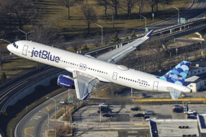 An air-to-air shot taken from a helicopter of a jetBlue A321neo banking out of JFK Airport.